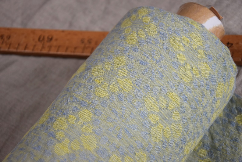 Pure linen fabric Flora Breezy. Floral geometric jacquard pattern woven from pastel yellow and pastel blue colors. Pattern repeats at each 6cm. The oposite sides of the fabric are different but both sides can be used as a right side.