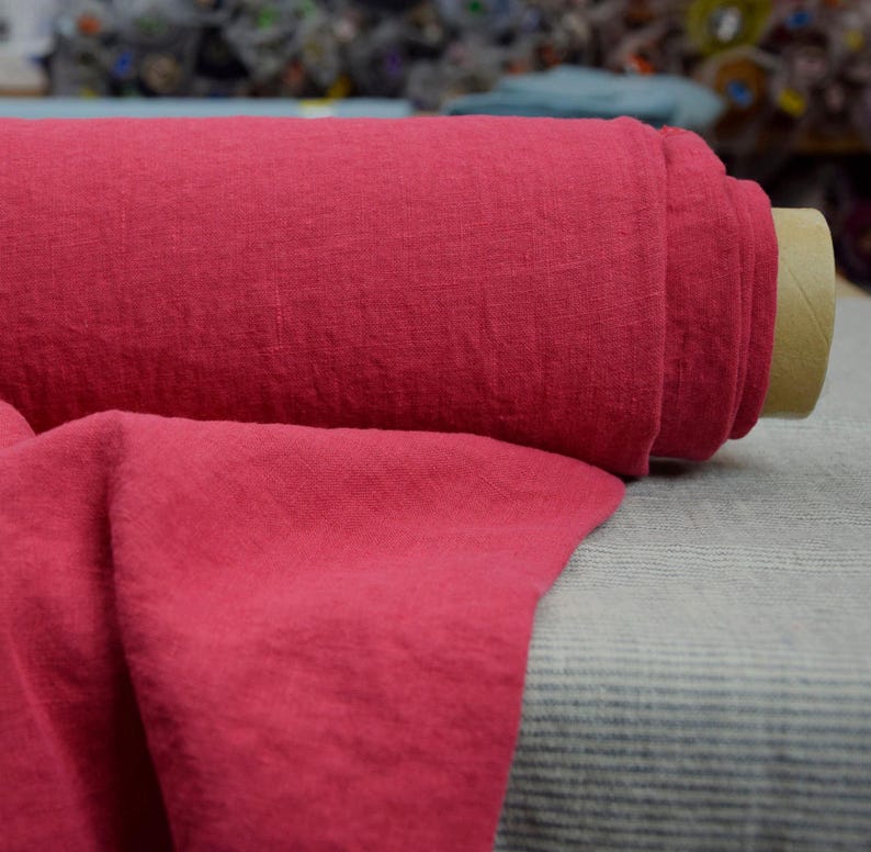May include: A roll of bright pink linen fabric. The fabric has a textured, slightly wrinkled appearance.