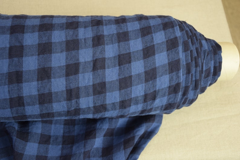 K&ouml;nnte beinhalten: Eine Rolle blauer und schwarzer Gingham-Stoff. Der Stoff hat ein kariertes Muster und ist aus Leinen.