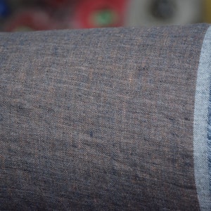 May include: A roll of dark blue linen fabric with a frayed edge. The fabric has a textured, woven appearance.