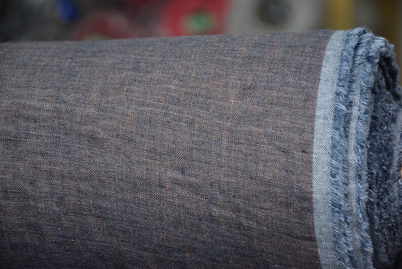 May include: A roll of dark blue linen fabric with a frayed edge. The fabric has a textured, woven appearance.