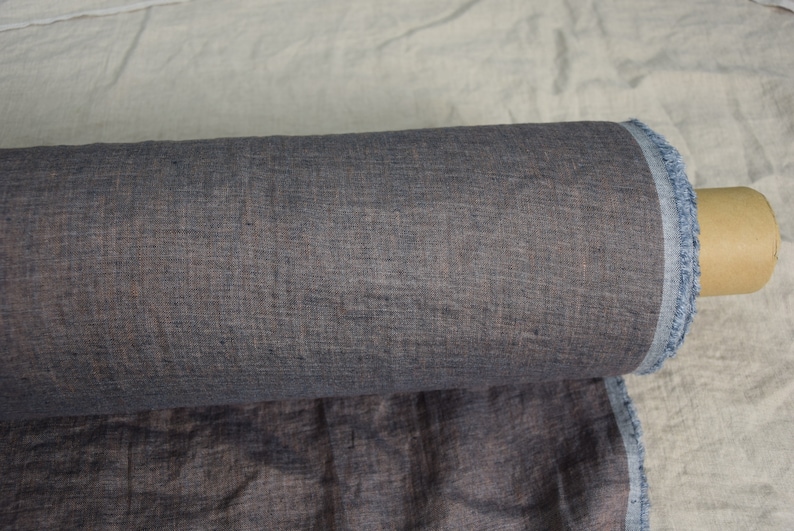 May include: A roll of dark gray linen fabric with a subtle texture. The fabric is rolled up and secured with a brown cardboard tube.