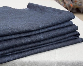 May include: A stack of dark blue linen fabric folded neatly on a white surface.
