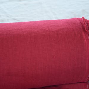 May include: A roll of deep red linen fabric with a frayed edge.