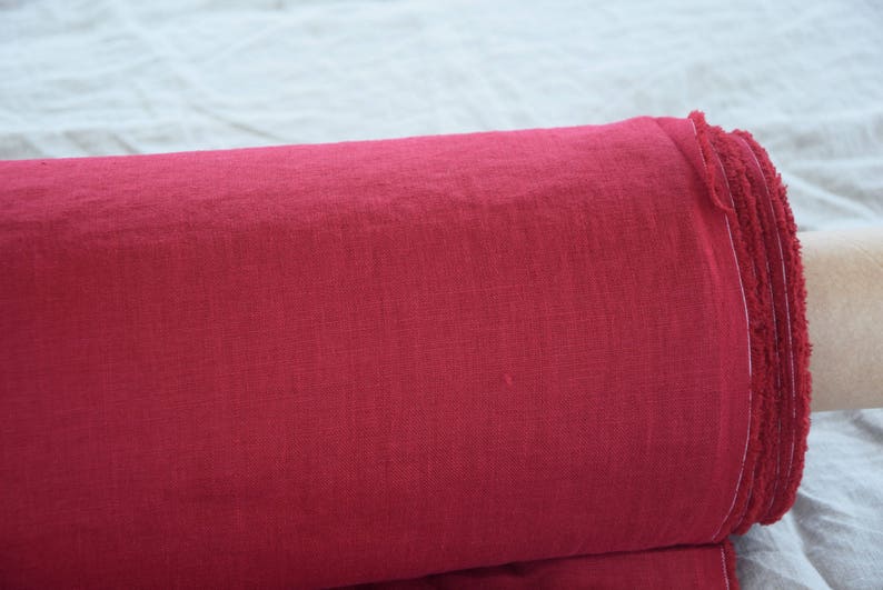 May include: A roll of deep red linen fabric with a frayed edge.