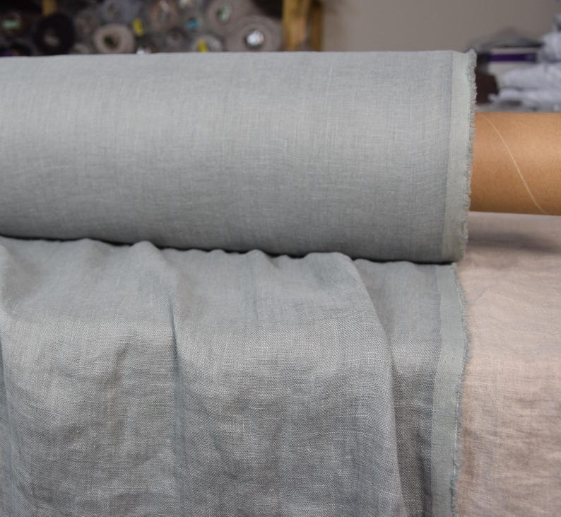 May include: A roll of light blue linen fabric. The fabric is soft and has a natural texture.