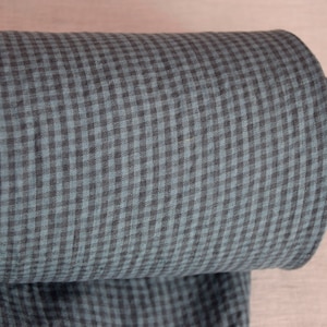 May include: A roll of fabric featuring a teal and black gingham pattern. The fabric is tightly rolled, revealing the pattern's repeating squares. The roll's core is a light brown cardboard tube.