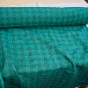 May include: A roll of teal fabric with a dark teal plaid pattern. The fabric is partially unrolled, revealing the plaid design. The fabric is likely used for sewing, crafting, or home decor projects.