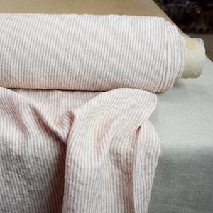 May include: A roll of pink and white striped linen fabric. The fabric is soft and has a subtle texture.