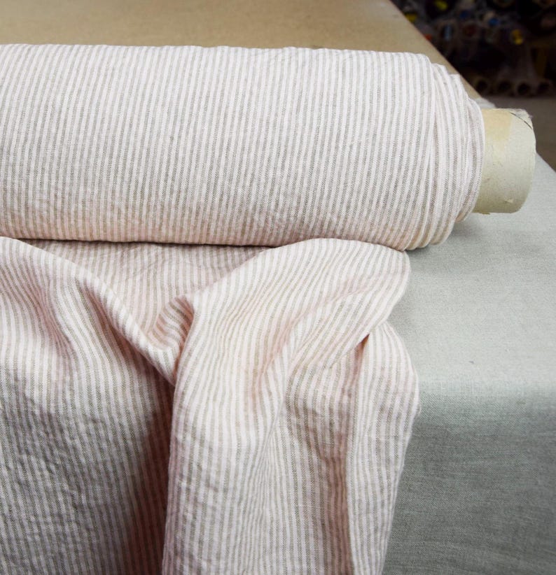 May include: A roll of pink and white striped linen fabric. The fabric is soft and has a subtle texture.