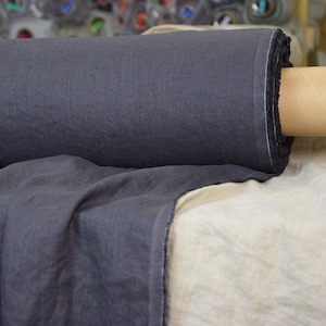 May include: A roll of dark gray linen fabric, folded and displayed on a white linen surface.