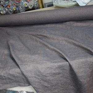 May include: A roll of dark gray fabric with a subtle texture. The fabric is unrolled and draped over a surface.