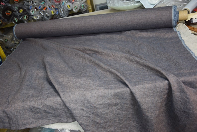 May include: A roll of dark gray fabric with a subtle texture. The fabric is unrolled and draped over a surface.