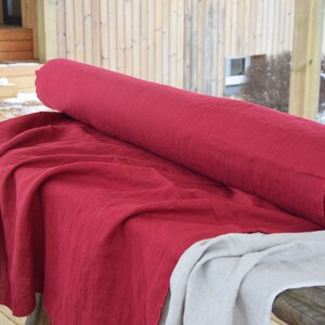May include: A roll of red linen fabric on a table. The fabric is folded and has a natural texture.