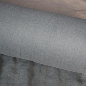 May include: A roll of light gray linen fabric. The fabric has a subtle texture and is perfect for sewing projects.