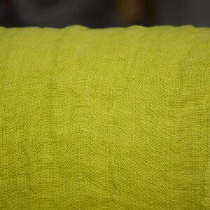 May include: A close-up of a bright green linen fabric. The fabric has a woven texture and a slightly rough feel.