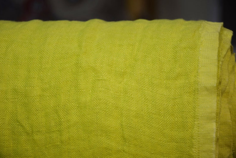May include: A close-up of a bright green linen fabric. The fabric has a woven texture and a slightly rough feel.