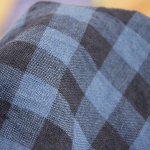 K&ouml;nnte beinhalten: Nahaufnahme eines blau-schwarzen karierten Stoffes. Der Stoff f&uuml;hlt sich weich und strukturiert an.