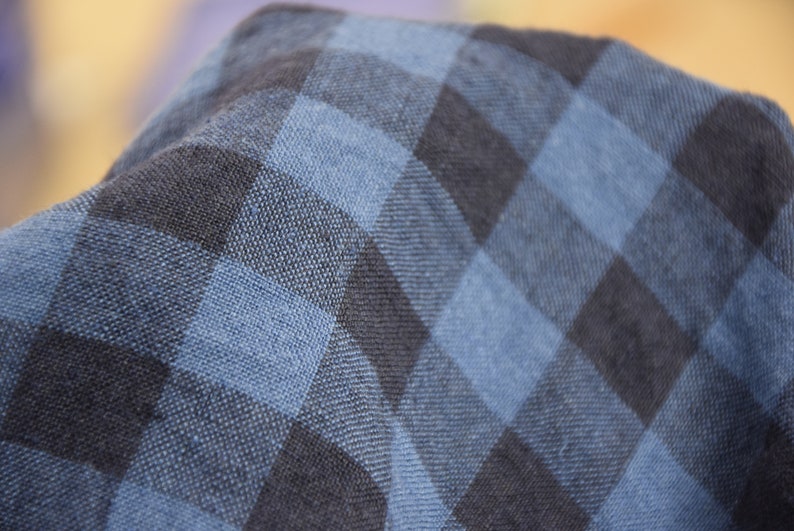 K&ouml;nnte beinhalten: Nahaufnahme eines blau-schwarzen karierten Stoffes. Der Stoff f&uuml;hlt sich weich und strukturiert an.