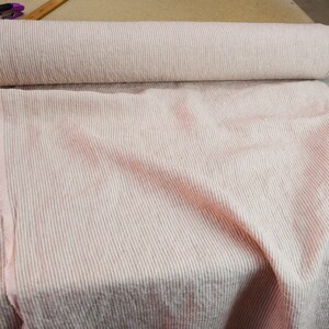 May include: A roll of pink and white striped fabric. The fabric is a linen blend and has a textured surface.