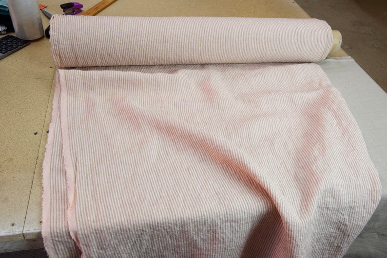 May include: A roll of pink and white striped fabric. The fabric is a linen blend and has a textured surface.