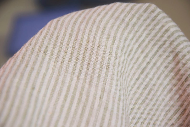May include: Close-up of a white and beige striped fabric with a subtle texture. The fabric has a woven appearance and a soft, natural feel.