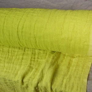 May include: A roll of bright yellow fabric with a crinkled texture. The fabric is folded and rolled up, and the end of the roll is visible.