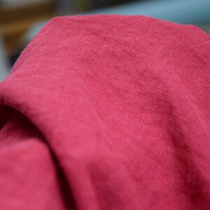 May include: A close-up of a soft, pink fabric with a textured surface. The fabric is folded and draped, creating a smooth, flowing look.