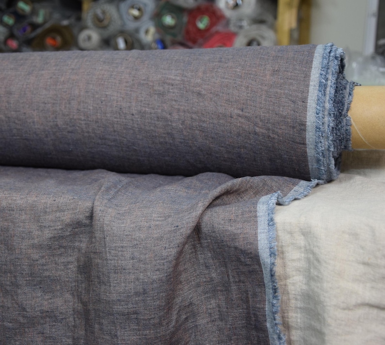 May include: A roll of dark blue linen fabric with a slightly textured surface. The fabric is folded in half and the edges are frayed.