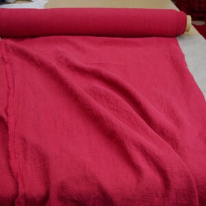 May include: A roll of bright red fabric, folded and laid out on a table. The fabric has a linen texture and is a solid color.