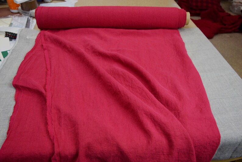 May include: A roll of bright red fabric, folded and laid out on a table. The fabric has a linen texture and is a solid color.