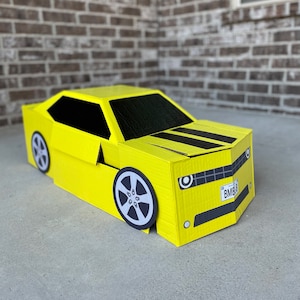 May include: A yellow cardboard car costume with black stripes and a license plate that reads "BMB9".