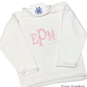 May include: White knitted sweater with long sleeves and a pink embroidered monogram "EPM". The sweater has a crew neck and a ribbed texture. The text "Font: Sanibel Thread: Cotton Candy" is visible at the bottom of the image.