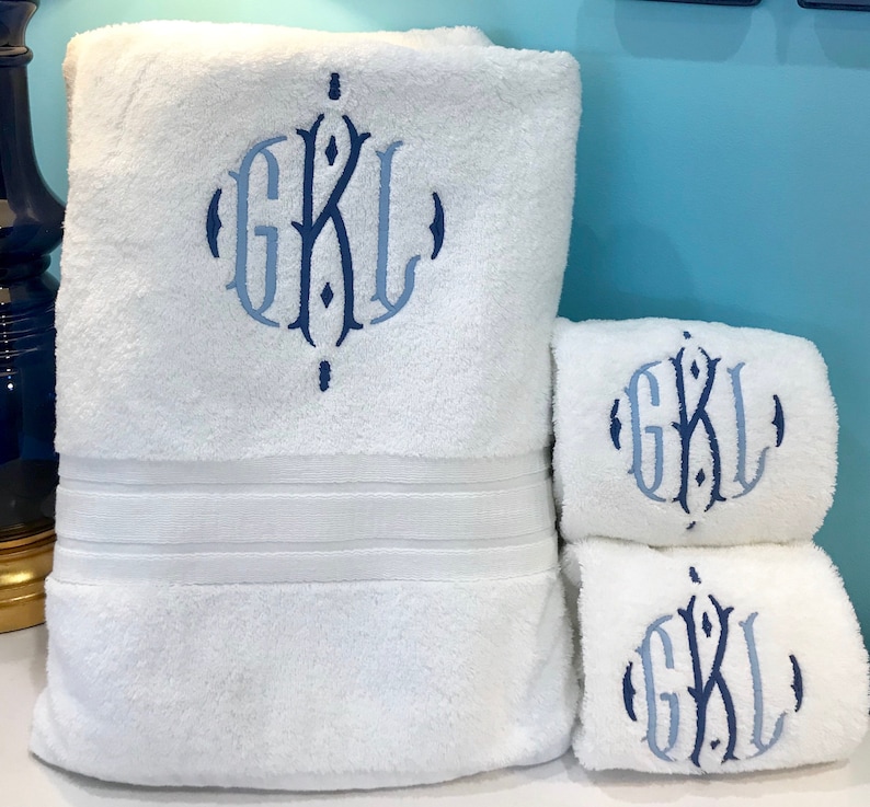 May include: Three white bath towels with blue embroidered initials "GKL" in a decorative font.