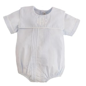 May include: A light blue baby romper with a white sailor collar and white piping. The romper has a white embroidered monogram "BHC" on the front.