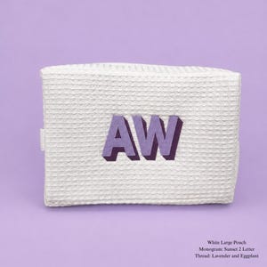 May include: A white large pouch with a waffle-textured fabric surface. The pouch features the embroidered letters AW in lavender and eggplant thread. The text on the image reads: White Large Pouch, Monogram: Sunset 2 Letter, Thread: Lavender and Eggplant.