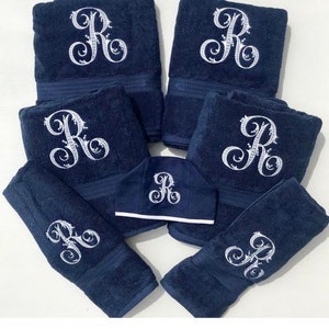 May include: Set of seven navy blue towels with white embroidered letter "R" in a decorative script. The set includes six bath towels and one hand towel.