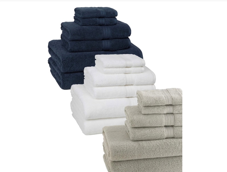 May include: A set of towels in three colors: navy blue, white, and gray. The towels are folded and stacked in a pyramid shape.