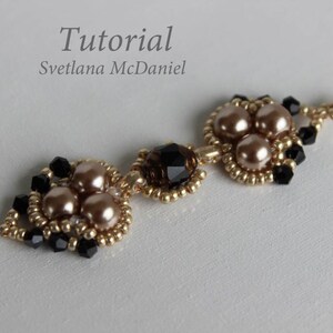 May include: Gold tone earrings with black and beige beads. The earrings feature a cluster of three beige beads surrounded by black beads. The earrings are connected by a gold tone chain with a single black bead.