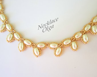 May include: A delicate gold necklace with white oval beads arranged in a leaf pattern. The necklace is labeled "Necklace Olga".