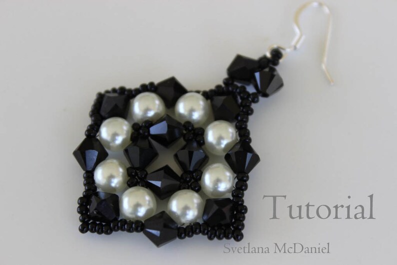 May include: A handmade earring featuring a square design with black and white beads. The earring is composed of black faceted beads, white pearl beads, and small black seed beads. The word "Tutorial" is visible in the image.