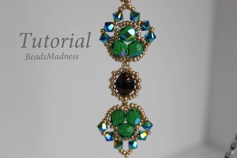 May include: A beaded pendant with green and blue crystals, gold beads, and a brown crystal in the center. The pendant is hanging from a gold chain. The text "Tutorial BeadsMadness" is visible in the top left corner of the image.