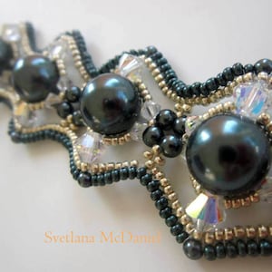 May include: A dark green and gold beaded bracelet with large black pearls. The bracelet has a wavy design and is made with small seed beads.