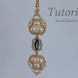 May include: Gold beaded earrings with a teardrop-shaped blue gemstone and white pearl accents. The earrings are hanging from a gold hook.