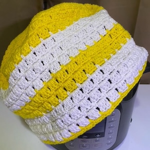 May include: Yellow and white striped crocheted cover for a slow cooker. The cover is made with a simple stitch pattern and has a relaxed, casual look.