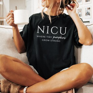 Puede incluir: Una camiseta negra con texto blanco que dice "NICU Where Tiny Pumpkins Grow Strong".
