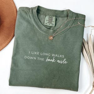 May include: A green t-shirt with the text "I like long walks down the book aisle" in white lettering.