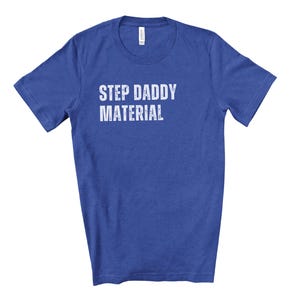K&ouml;nnte beinhalten: Ein k&ouml;nigsblaues T-Shirt mit dem Aufdruck "STEP DADDY MATERIAL" in Wei&szlig;.