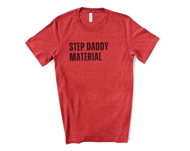 K&ouml;nnte beinhalten: Rotes T-Shirt mit kurzen &Auml;rmeln und dem Aufdruck "STEP DADDY MATERIAL" in Schwarz.