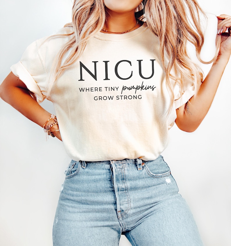 Puede incluir: Una camiseta blanca con el texto "NICU Where Tiny Pumpkins Grow Strong" impreso en la parte delantera.